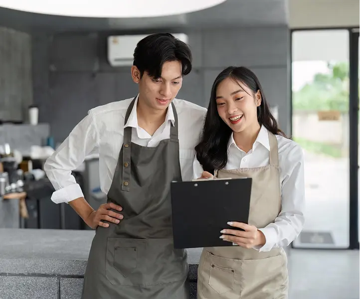 A man and woman going over our clipboard checking on their inventory for the restaurant.