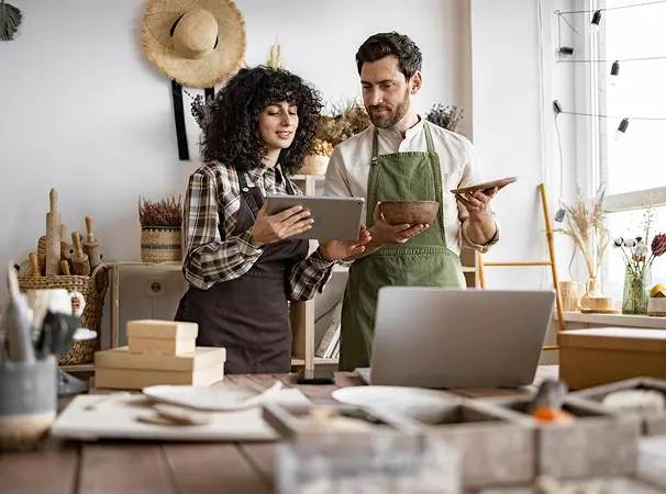 A man and a woman business owner, looking at their iPad and ordering products for their shop.
